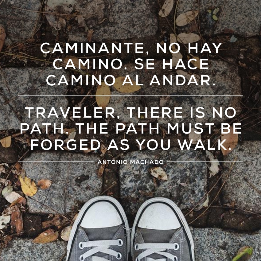 gray sneakers on cobblestones with the quote "Traveler, there is no path. The path must be forged as you walk." in both Spanish and English