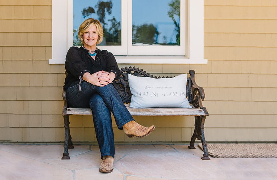 Brené Brown sitting on bench outside of yellow building