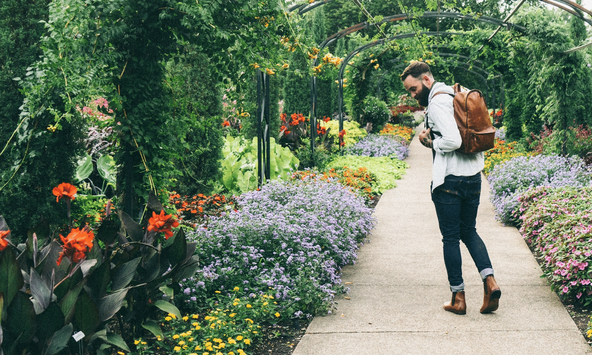 Man walking in garden with leather backpack
