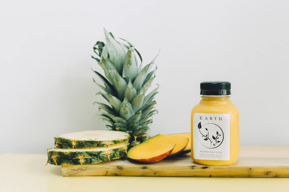 slices of pineapple and container of pineapple juice sitting on table