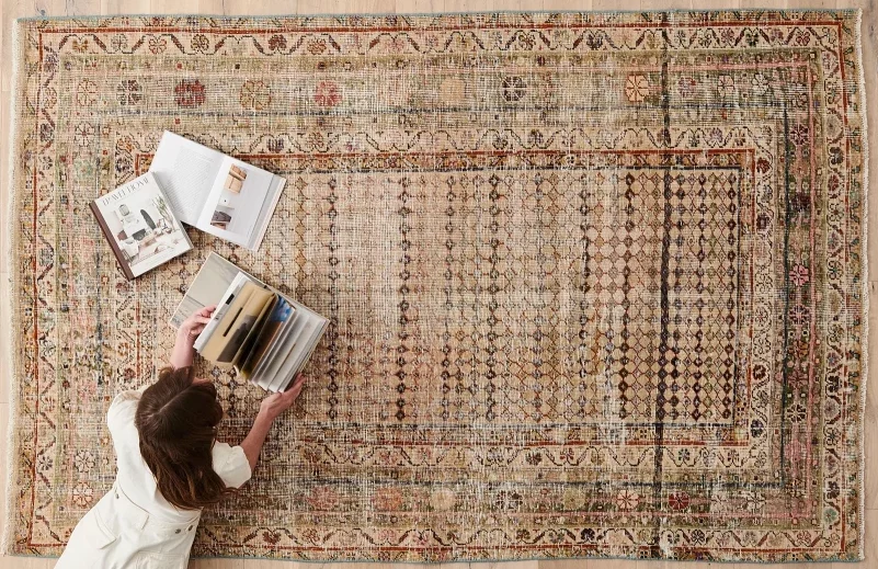 Woman reading books while laying on a rug